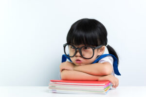 Little Asian girl wearing eyeglasses with books